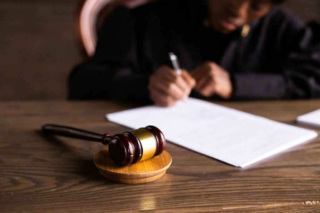 Judge signing documents at desk with focus on gavel, representing law and justice.