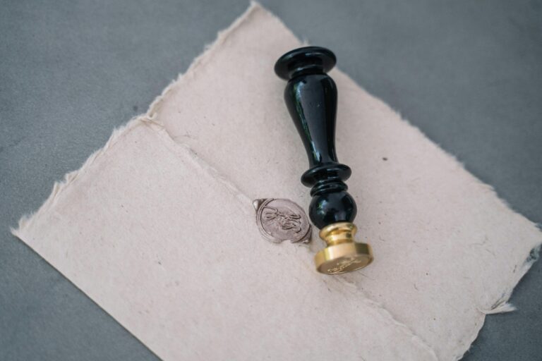 Close-up of a vintage wax seal on a rustic paper envelope with a black sealing stamp.