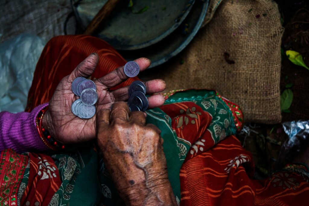 Close-up of an elderly woman's hands counting coins on a colorful textile background.