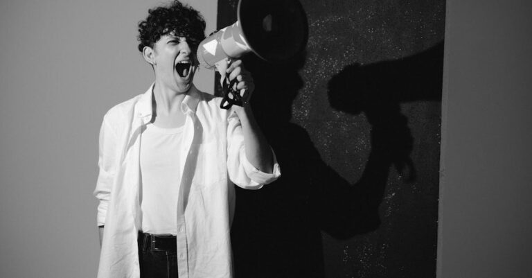 A black and white image of a person passionately shouting with a megaphone, symbolizing activism.
