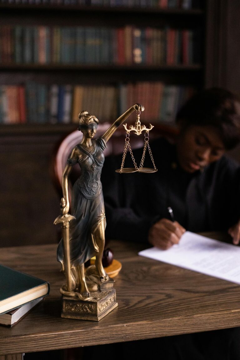 Close-up of Lady Justice figurine on a lawyer's desk with books and documents.