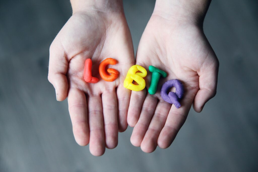 Close-up of hands holding colorful letters representing LGBTQ pride.