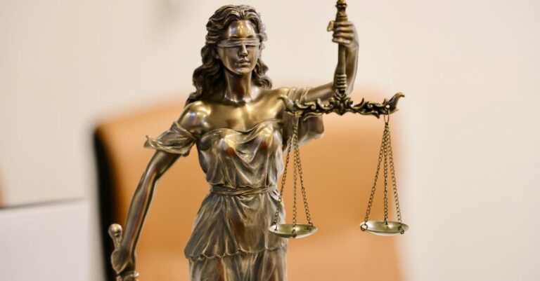 Close-up of Lady Justice statue holding scales, symbolizing justice and fairness.