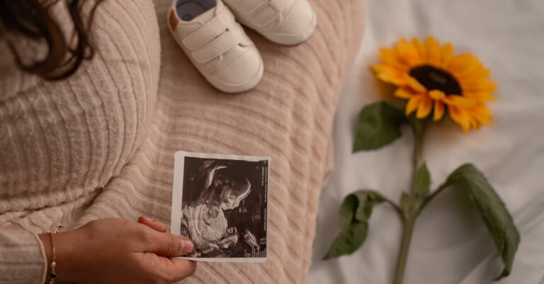 Expectant mother holding an ultrasound with baby shoes and a sunflower, symbolizing new beginnings.