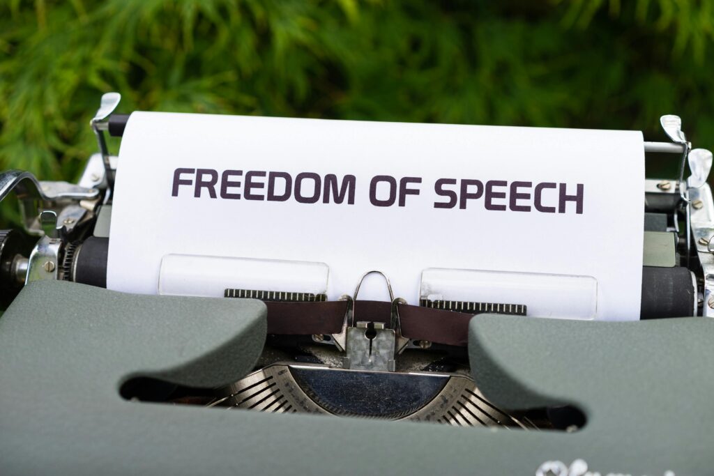 Close-up of typewriter with 'Freedom of Speech' message on paper, evoking themes of journalism and expression.