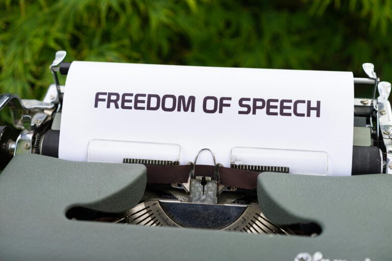 Close-up of typewriter with 'Freedom of Speech' message on paper, evoking themes of journalism and expression.