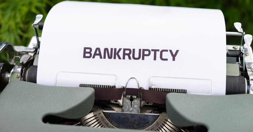 Close-up of a typewriter with the word 'BANKRUPTCY' on paper, surrounded by greenery.