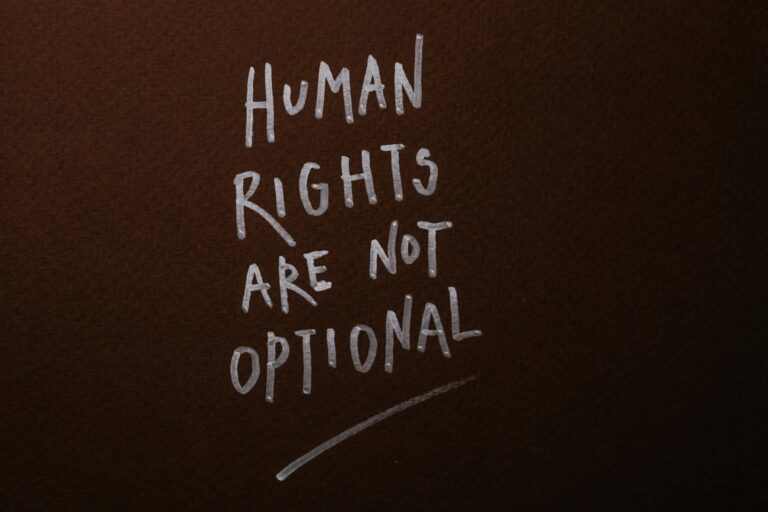 Handwritten message advocating for human rights on a rich brown background.