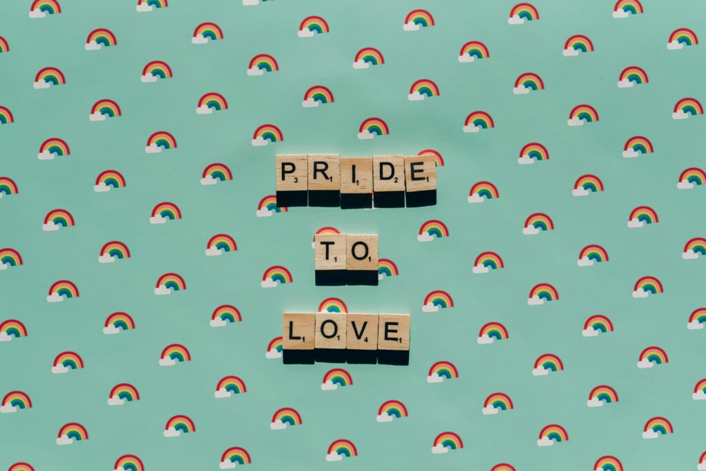 Scrabble tiles spelling 'Pride to Love' on a rainbow background, celebrating LGBT pride.