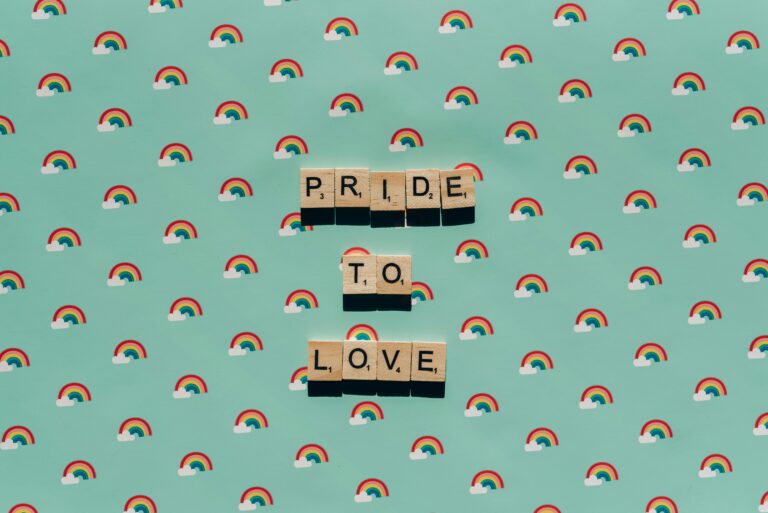 Scrabble tiles spelling 'Pride to Love' on a rainbow background, celebrating LGBT pride.