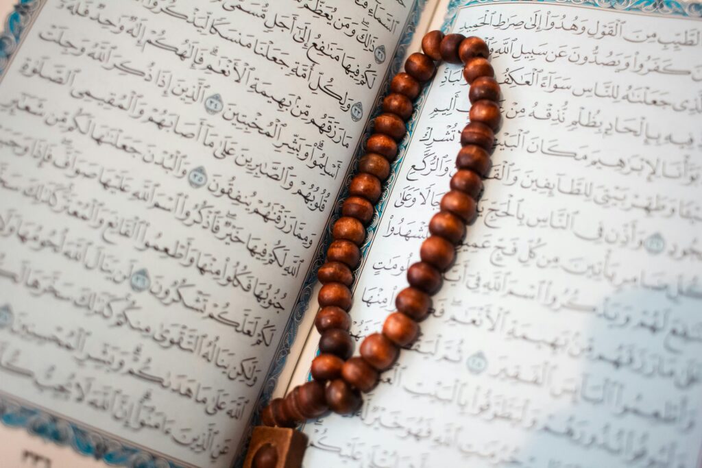 An open Quran page with wooden prayer beads, showcasing Islamic calligraphy and spiritual symbolism.