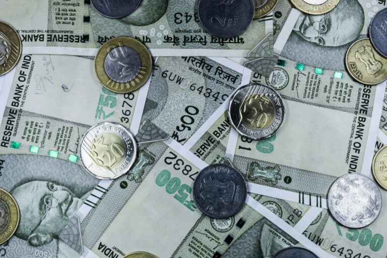 Top view of various Indian rupee banknotes and coins, highlighting financial themes.