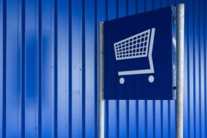 Blue metal wall with a shopping cart sign symbolizing retail or supermarket area.